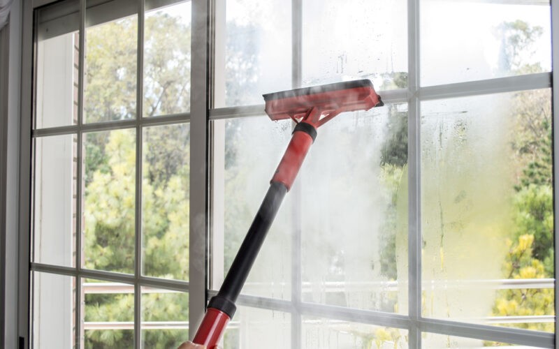 Čištění okna dlouhým červeným parním čističem