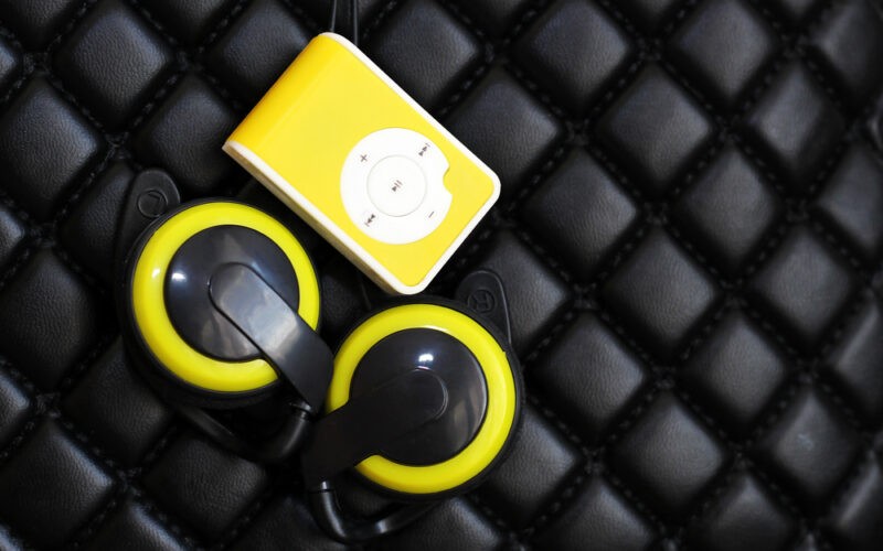 Žlutý mp3/mp4 přehrávač s černo-žlutými sluchátky na černo pozadí