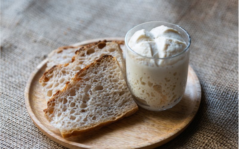 pšeničný kvásek lievito madre ve sklenici, krajíce kváskového bílého chleba