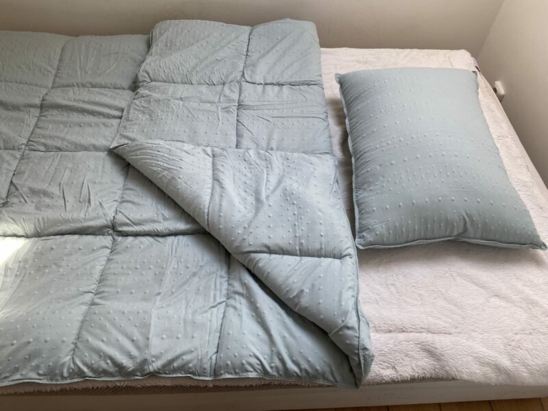 Set zeleného polštáře a přikrývky na posteli