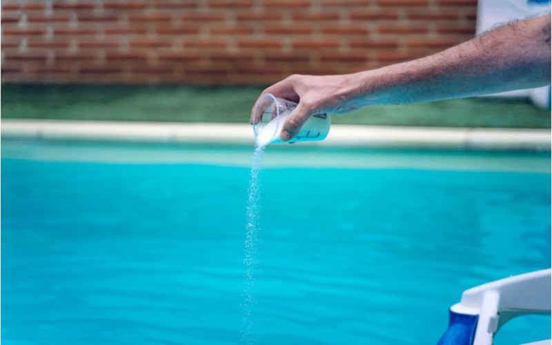 Zazimování bazénu - dávkovač bazénové chemie v mužské ruce