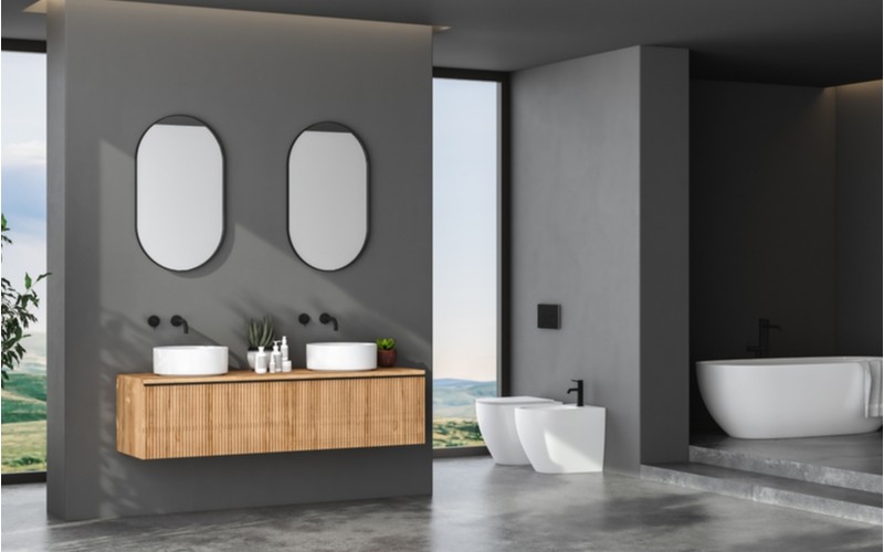 světlá koupelna s dřevěnou skříňkou se dvěma kamennými umyvadly
