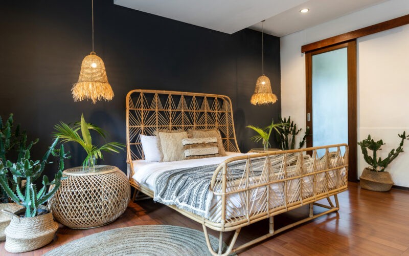 ložnice se stěnou černou barvy zařízená s použitím přírodních materiálů - ratanový noční stolek